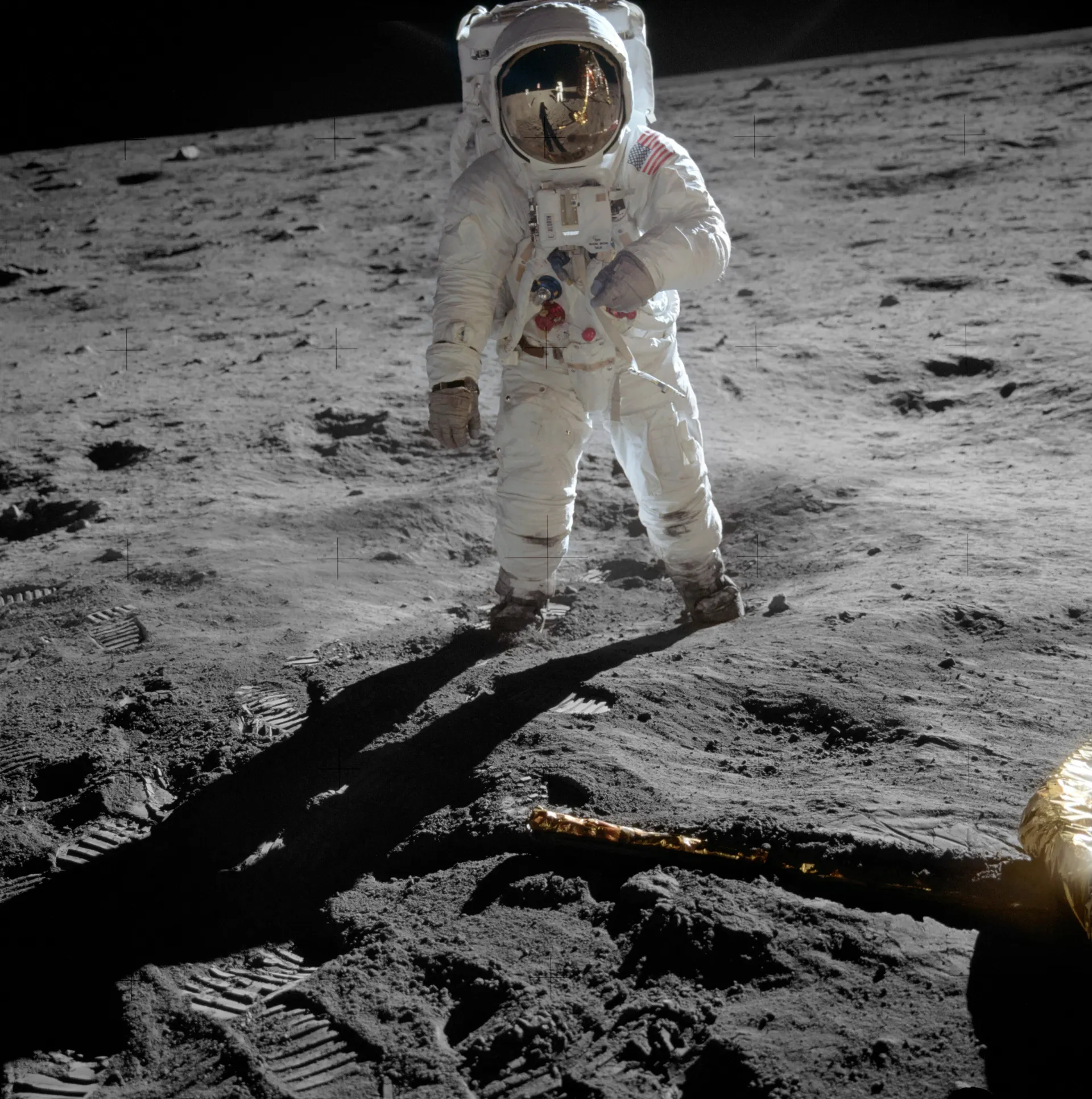 Buzz Aldrin na powierzchni Księżyca, w szybie hełmu odbija się Neil Armstrong i lądownik Eagle
